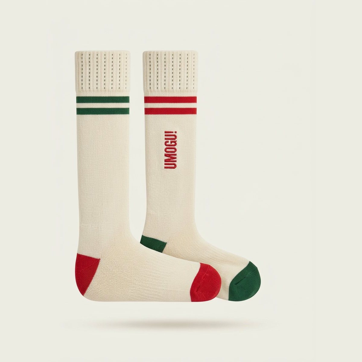 A pair of ivory crew socks with red and forest stripes, UMOGU! knitted on the leg.