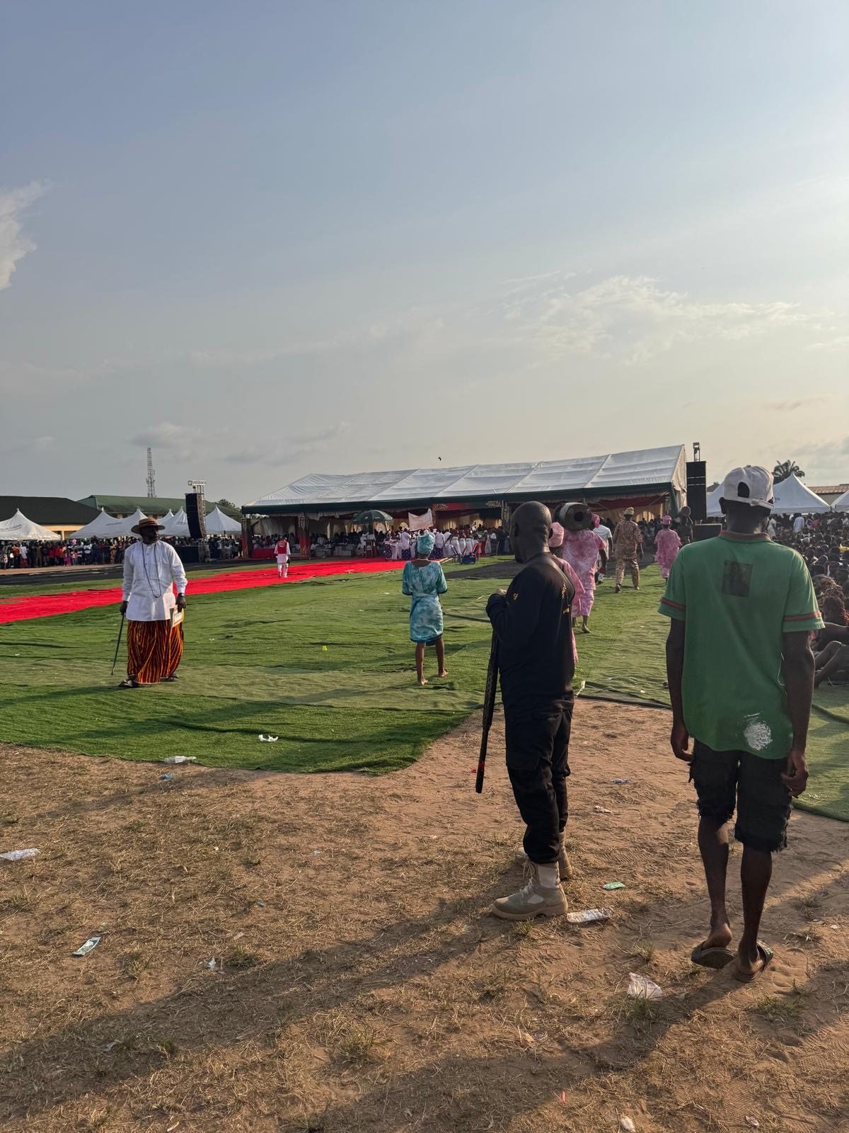A chief in white robes crossing the ground toward the carpet.