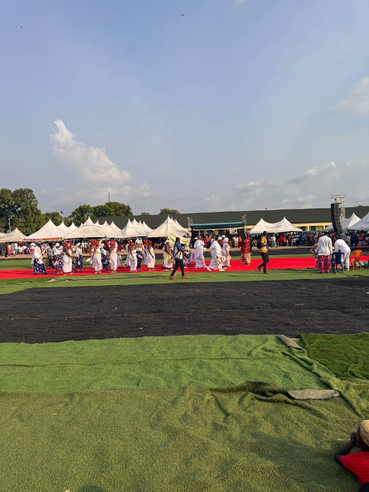 Women processing along the red carpet laid across the field.